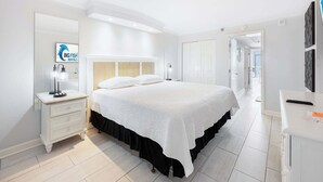 Une chambre à coucher comprenant un lit, une table de chevet, un miroir et une porte donnant sur une autre pièce.