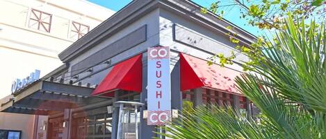 A sushi restaurant with a red awning and a sign that reads "SUSHI".