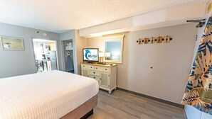 A hotel room with a bed, a television, a dresser, and a mirror.