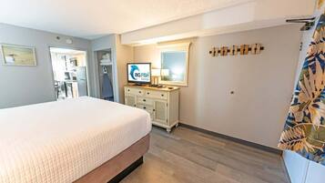 A hotel room with a bed, a television, a dresser, and a mirror.