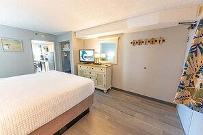 Une chambre d’hôtel avec un lit, une télévision, une commode et un miroir.