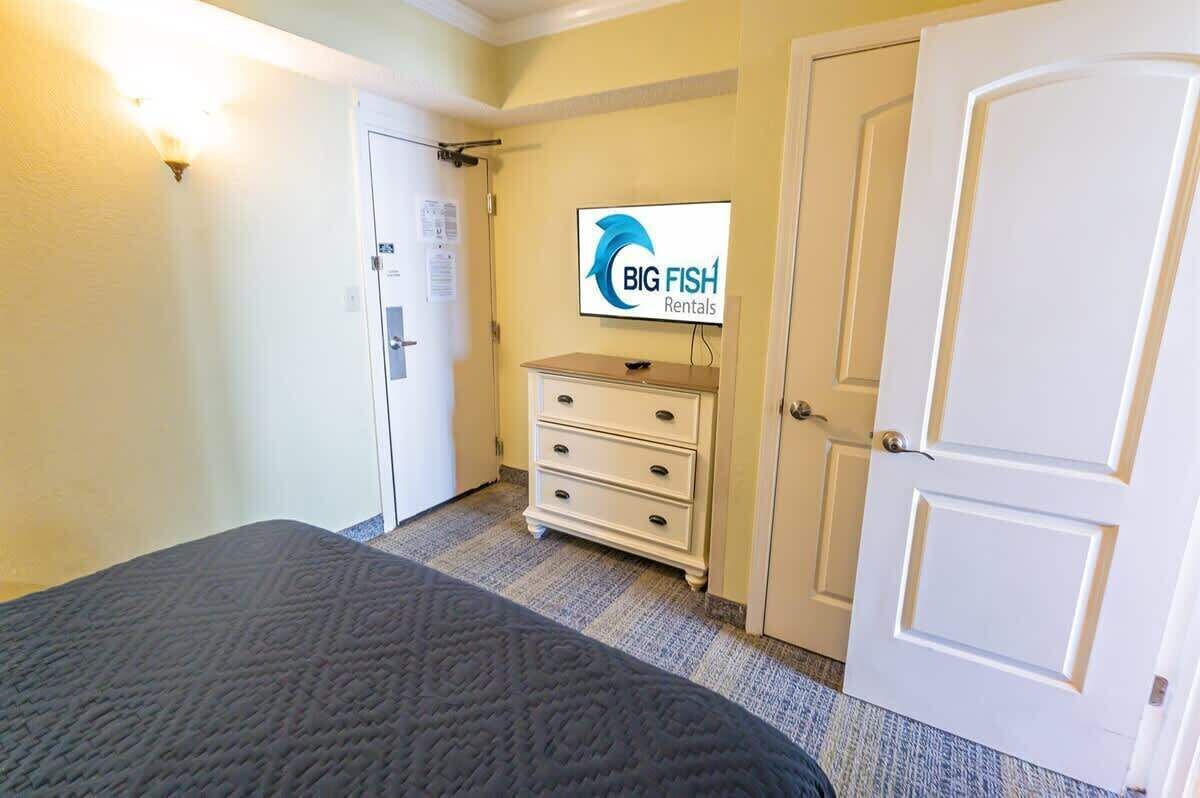 Une chambre d’hôtel avec un lit, une commode, une télévision et une porte.