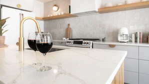 Ett modernt kök med en bänkskiva i marmor, en gasspis och en kaffebryggare.