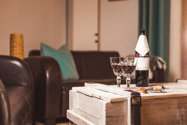 Une table en bois avec une bouteille de vin, deux verres et un tire-bouchon.