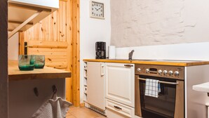 Een kleine keuken met een houten kast, een koffiezetapparaat, een klok en een kookplaat.
