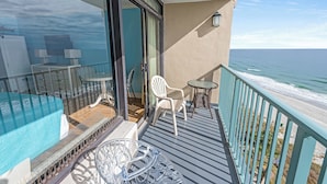 A balcony with a glass door, a white chair, a small table, and a view of the ocean. - New Direct Oceanfront,Heated Indoor Pool,Remodeled (Myrtle Beach)