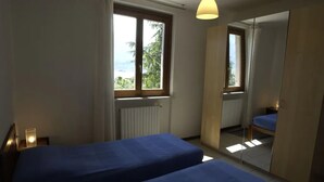 Een slaapkamer met twee bedden, een raam, een radiator en een spiegel.