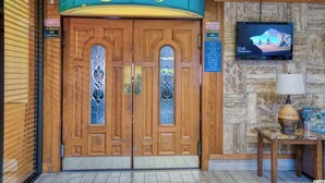 A wooden double door with a sign above it, a television mounted on the wall, and a table with a lamp. - Ocean Annie's Oceanview Studio,Scenic Views,Pools! (Myrtle Beach)