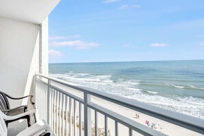 A balcony with a view of the ocean, white chairs, and a railing. - Nice Oceanfront Sea Mist Home with Beautiful Views (Myrtle Beach)