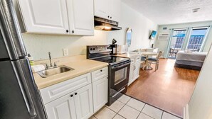 A compact kitchen with white cabinets, a stainless steel refrigerator, a stove, and a sink. - Amazing Views on High Floor at Beautiful Sea Mist (Myrtle Beach)