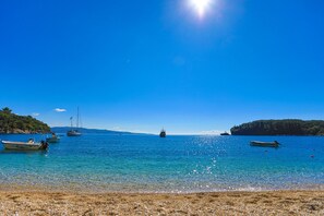A clear blue sea with boats and a beach.