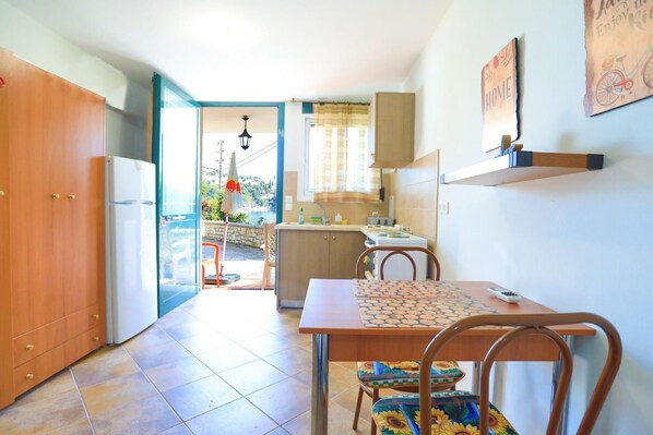 A compact kitchen with a dining area, a refrigerator, a sink, and a window overlooking a scenic view.