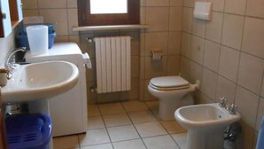 Ein kleines Badezimmer mit Waschbecken, Toilette, Bidet und einem Fenster für Tageslicht.