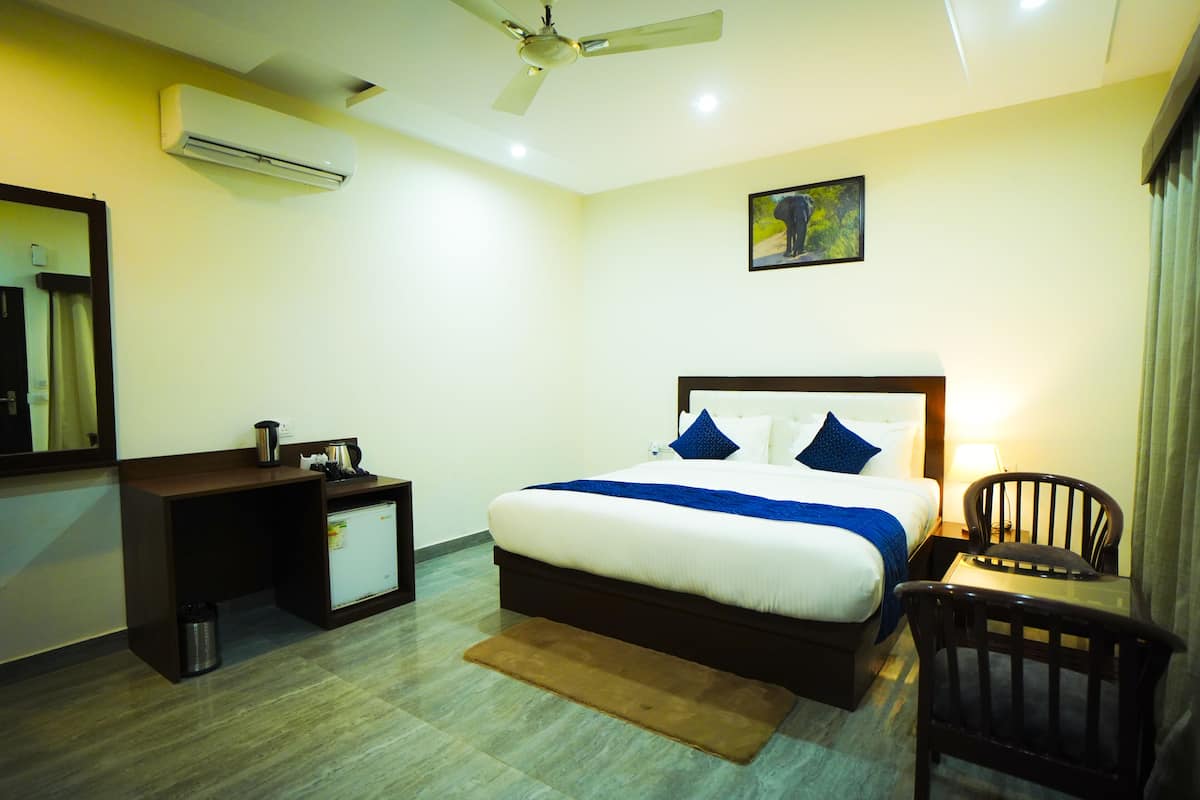 A hotel room with a bed, a desk, a chair, an air conditioner, and a ceiling fan.