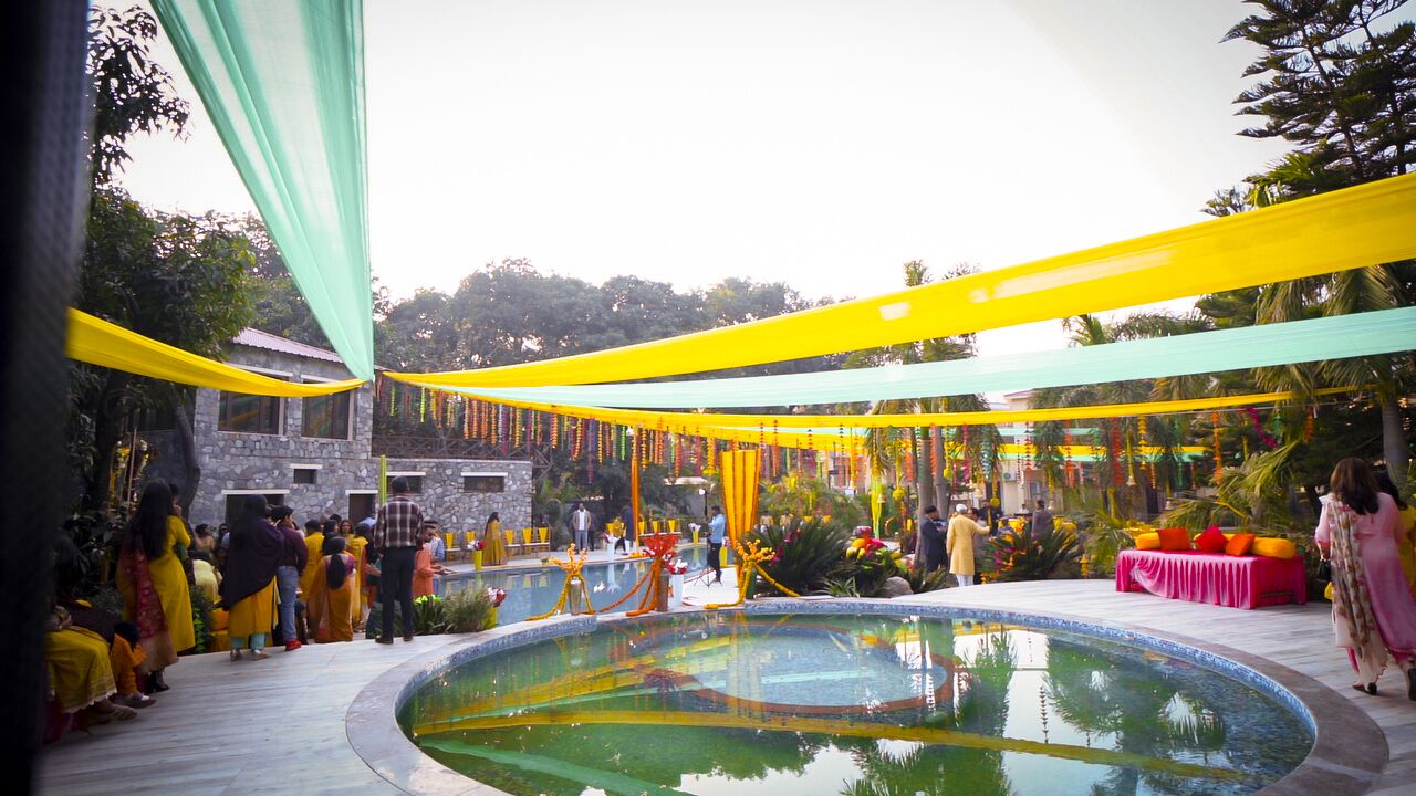 Zona de piscina con un edificio de piedra al fondo, rodeada de vegetación.