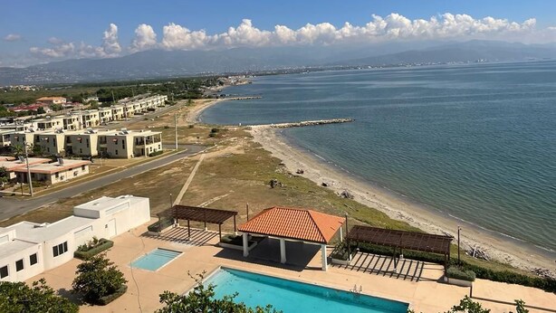 A coastal view with a swimming pool, beach, and buildings. - Sea Front Villa  (Pool AC Gated 24hrs Security) (St. Catherine Parish Bridgeport P.O)
