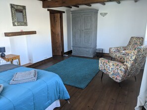 Une chambre à coucher avec un lit, une chaise, une armoire et un miroir.