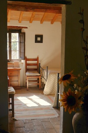 A rustic room with a wooden chair, a desk, a window, and a sunlit floor. - Restored Watermill with Rock Pool and Waterfall (San Giustino)