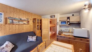 A compact room with a wooden bunk bed, a small kitchenette, and a dining table. - Cozy Apartment - Balcony with valley view - 5 minutes from the slopes (Montvalezan)