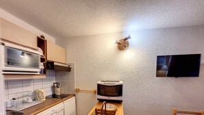 A compact kitchen with a microwave, toaster, and wooden counter. - Cozy Apartment - Balcony with valley view - 5 minutes from the slopes (Montvalezan)