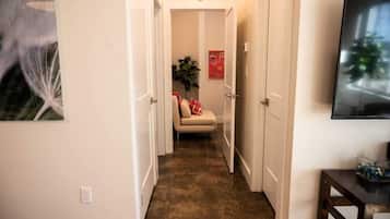 A hallway with a sofa, a plant, and a TV on a stand.