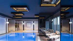 Una piscina interna moderna con vista chiara sulla zona, sedie a sdraio e un muro in mattoni sullo sfondo.