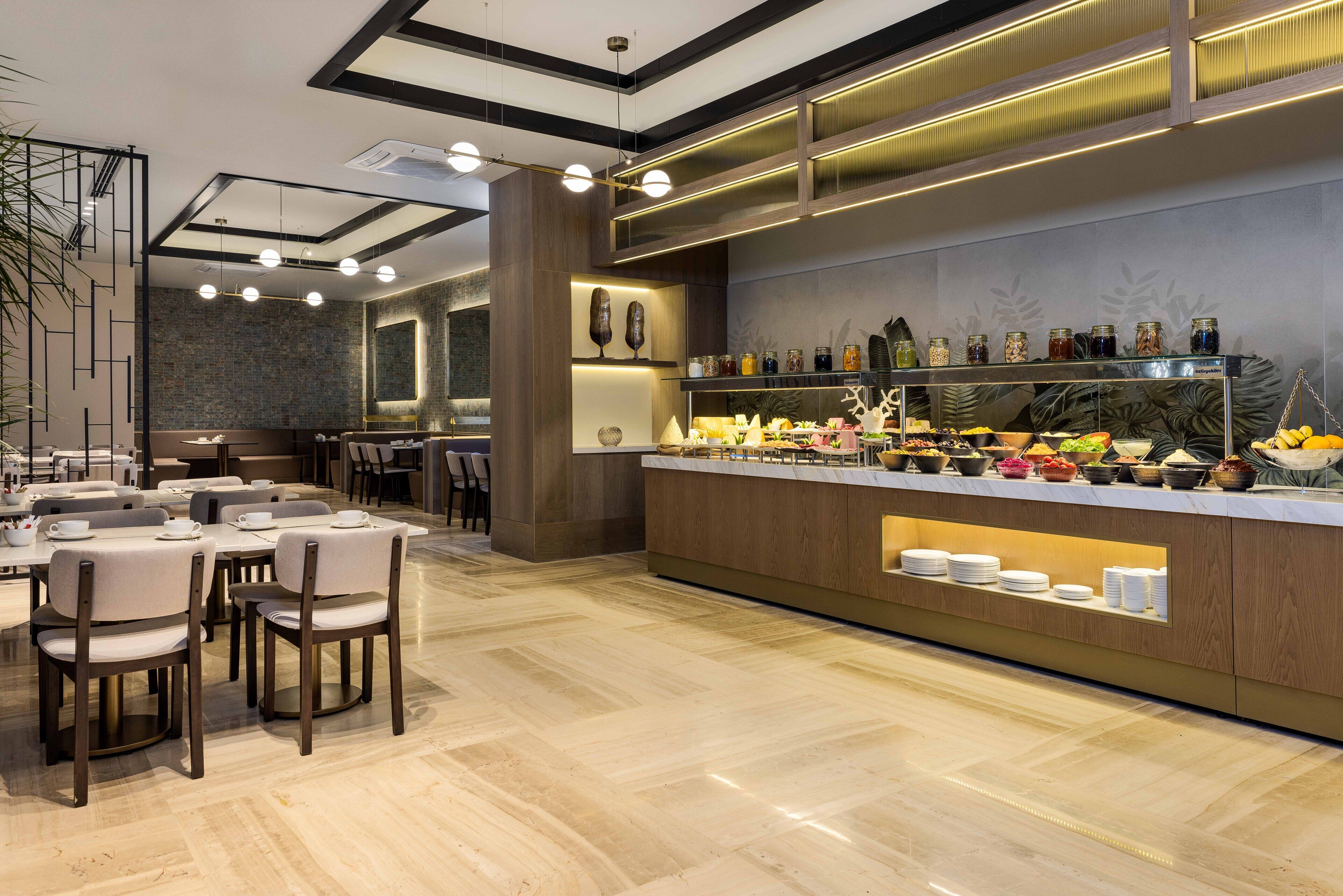 Un moderno comedor con una barra de buffet, varias mesas y sillas.