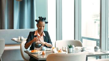 Una persona sentada a una mesa en un comedor moderno con vistas a la ciudad a través de amplios ventanales.
