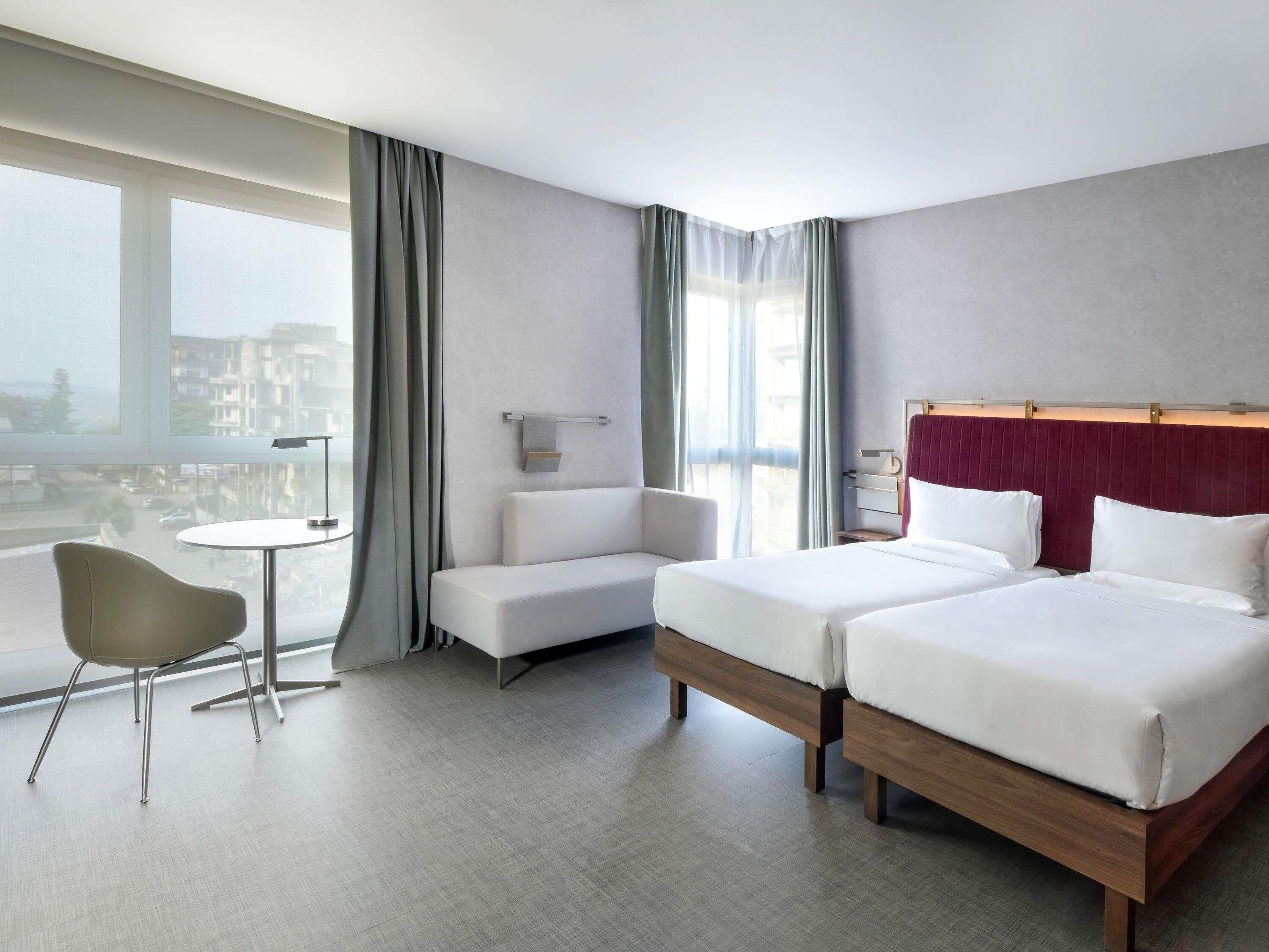 A hotel room with two beds, a sofa, a small table, and a chair.