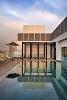 Un área de piscina en la azotea con sillones de descanso y una estructura de cristal.