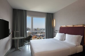 A hotel room with a large bed, a desk, a chair, and a TV. - Novotel Kinshasa La Gombe (Kinshasa)
