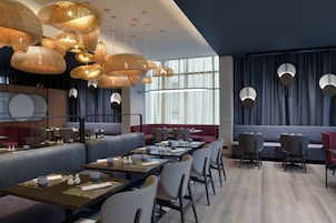 Un restaurante moderno con varias zonas de comedor, incluyendo un bar y mesas con sillas.