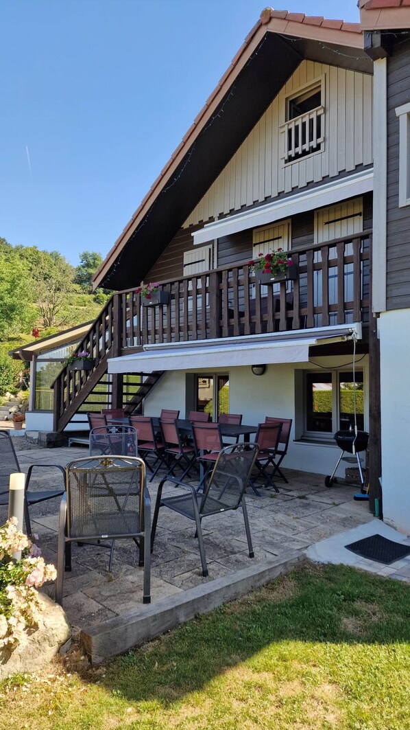 A two-story building with a balcony, outdoor seating area, and a grill.