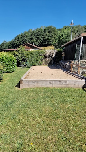 A garden with a sandbox, a wooden bench, and a metal fence.