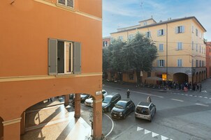 A street view with parked cars and a building with open shutters.