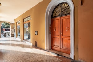 L'ingresso di un hotel con un'ampia porta in legno a due ante, vetrate e pavimento piastrellato.