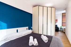 Una camera da letto moderna con un letto, un armadio e vista sulla città attraverso la finestra.