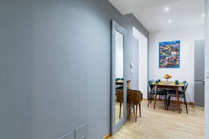 A modern dining area with a wooden table, chairs, and a colorful wall art piece.