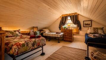 A cozy attic bedroom with a sloped ceiling, a wooden bed, a dresser, a chair, and a window with curtains.