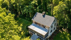 A two-story house with a large front porch and a covered patio area. - Riverfront Cabin! Farm, Fireplace & Kayaks (DB) (Luray)