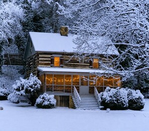 A log cabin with a front porch and a staircase leading to the entrance.