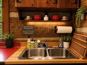A kitchen with a stainless steel sink, wooden cabinets, and a sign indicating a septic system. - Riverfront Cabin! Mini Highland Cows & Kayaks (DB) (Luray)