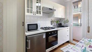 A compact kitchen with white cabinets, a microwave, a gas stove, and a refrigerator.