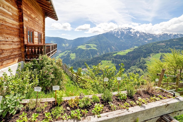 A wooden chalet with a balcony overlooking a mountainous landscape.