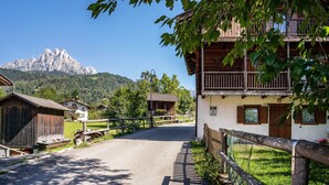 Un villaggio rurale con edifici in legno, una strada asfaltata e una montagna sullo sfondo.