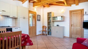 Una cucina con travi in legno, un tavolo da pranzo con tovaglia rossa e un divano rosso.