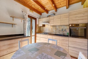 A kitchen with wooden cabinets, a tiled backsplash, a stove, and a sink. - Holiday Home 'Del Fiume' with Mountain View and Private Garden (Rialto)