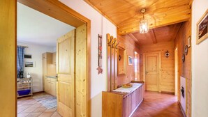 Un intérieur en bois comprenant un espace cuisine, des portes en bois et un sol carrelé.