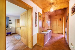 A wooden interior with a kitchen area, wooden doors, and a tiled floor.