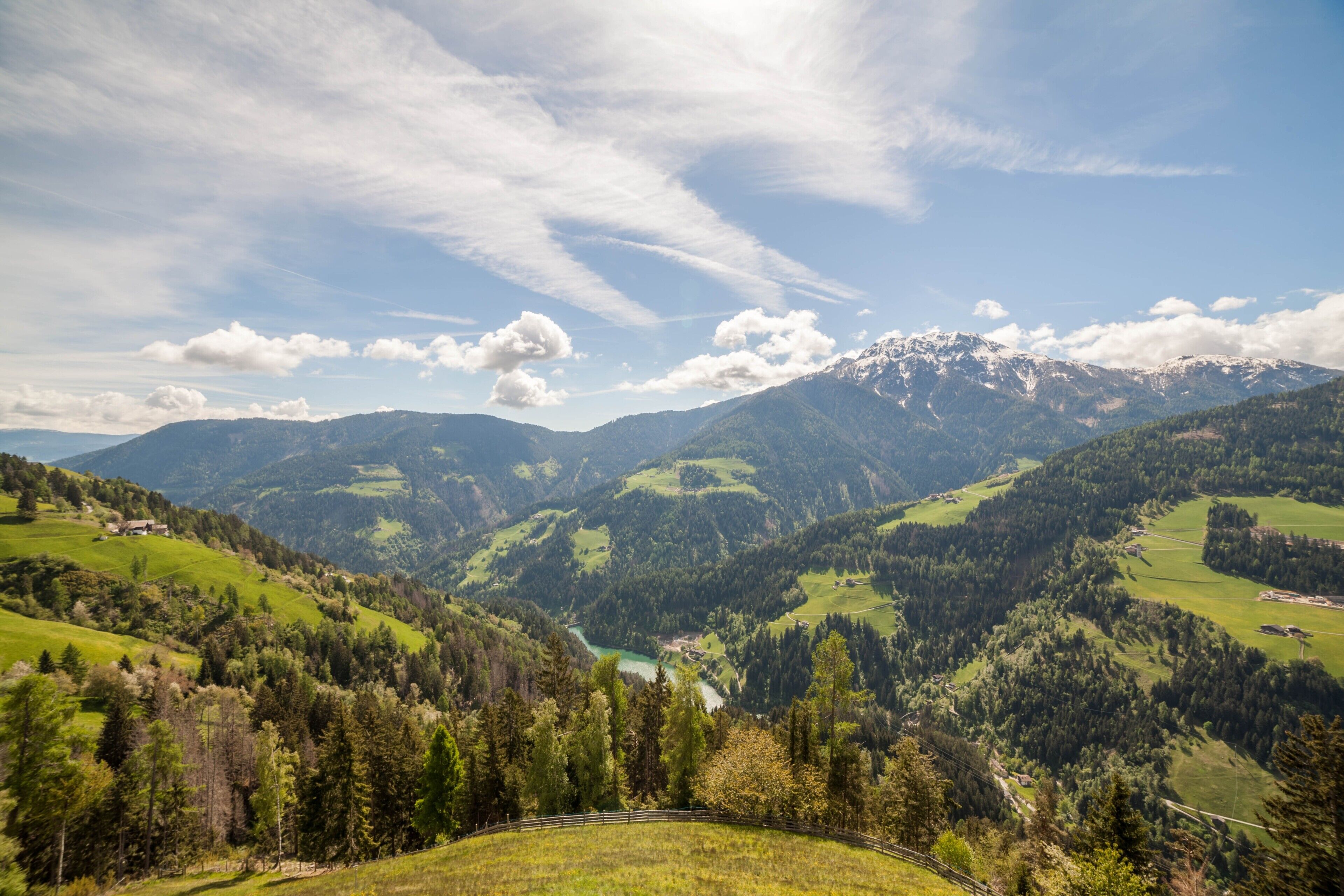 A mountainous landscape with a valley, a river, and a small building.